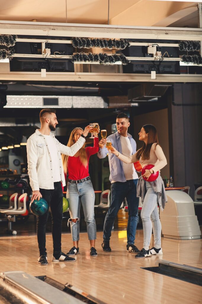 Group of friends toast with a beer in a bowling alley